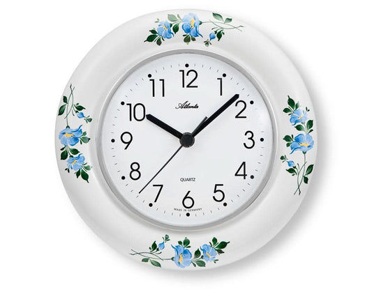 Keramisk väggklocka, rund, vit med blå blommor; urtavla och visare.