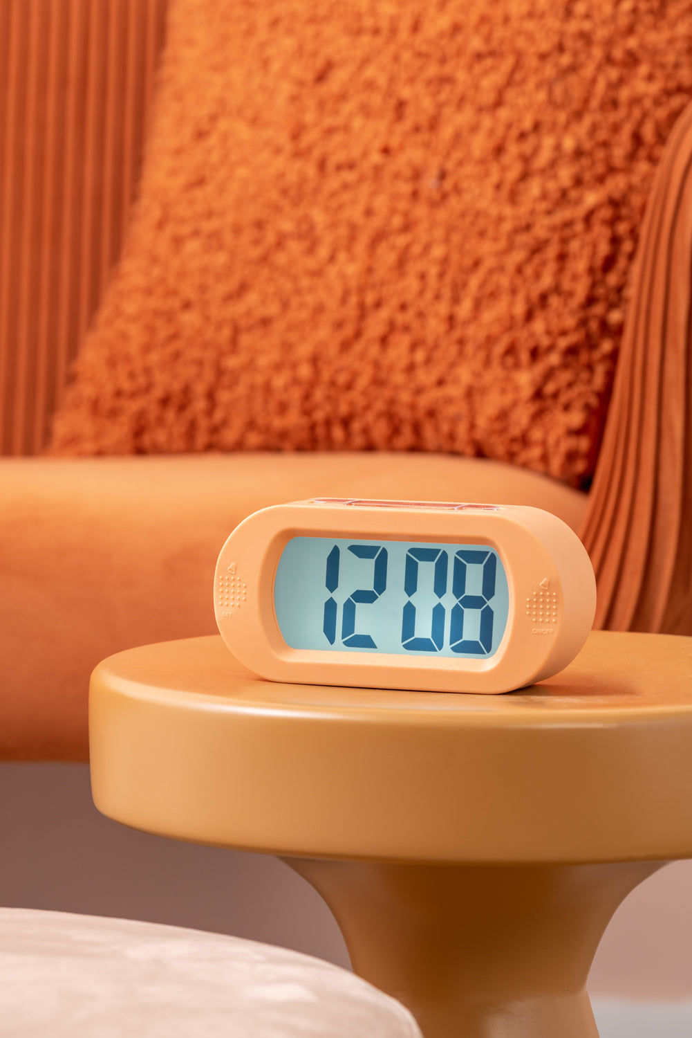 Digital väckarklocka i mjukorange med belyst LCD-display på nattduksbord