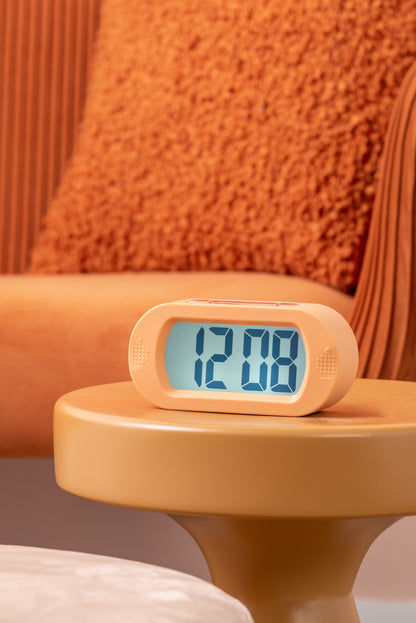 Digital väckarklocka i mjukorange med belyst LCD-display på nattduksbord