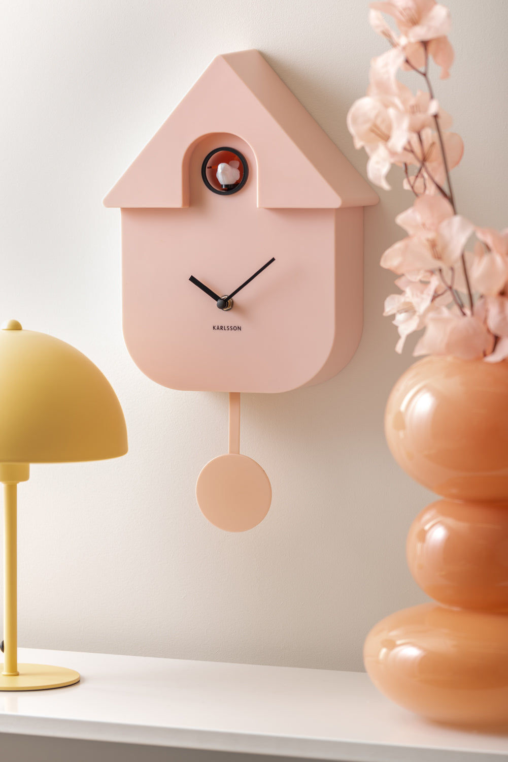 Rosa väggklocka i husdesign med pendel och gökurfönster