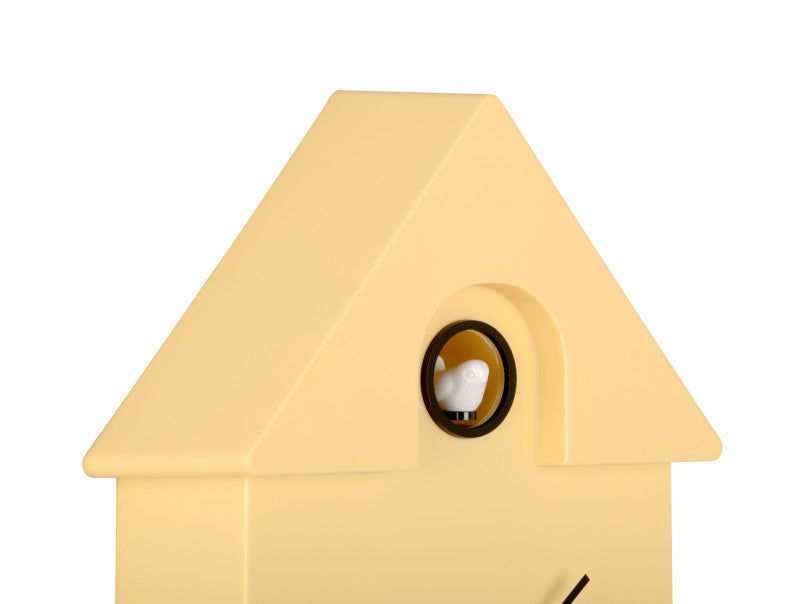 Väggklocka i fågelholksdesign, närbild av runt fönster på gult hölje
