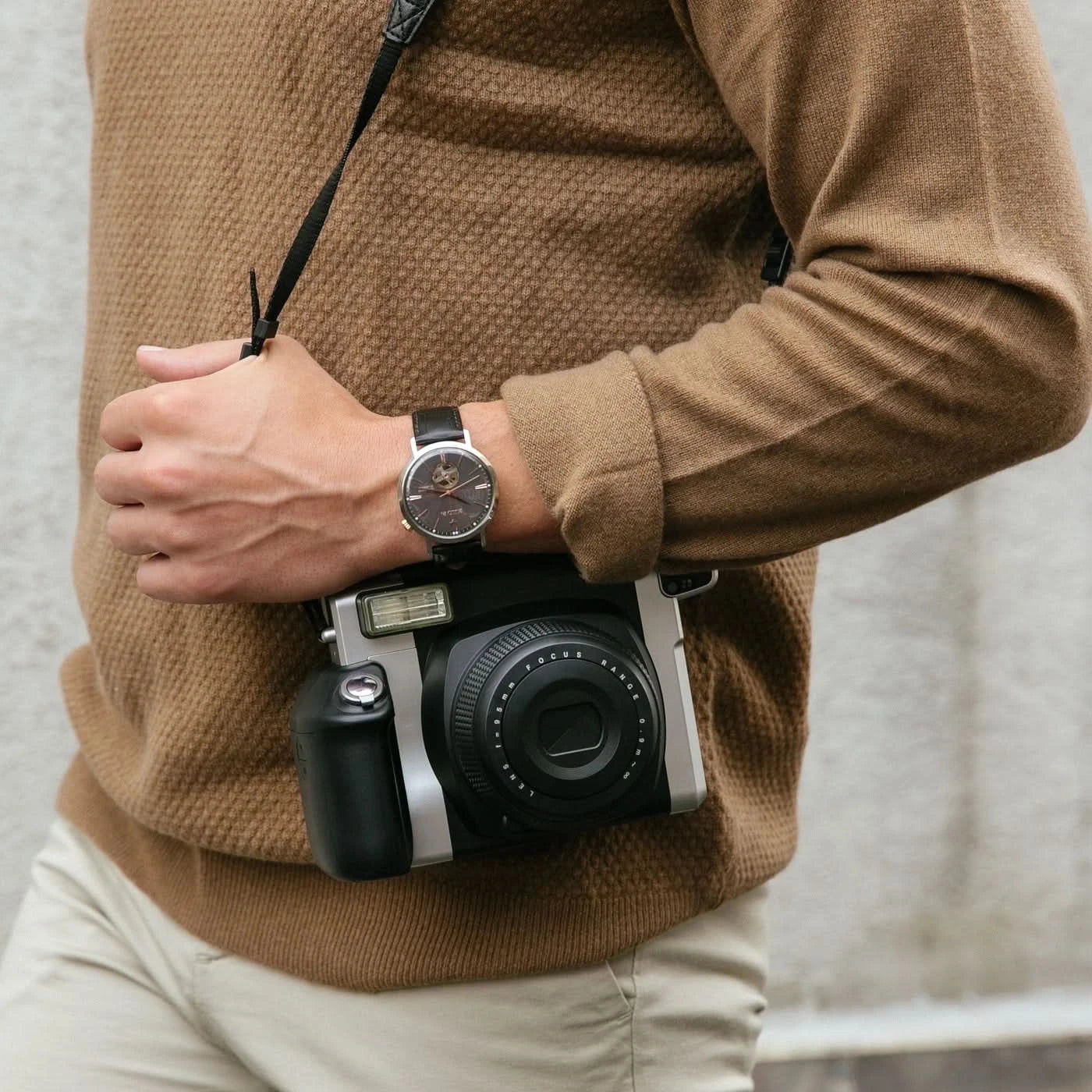 Herrklocka på handleden med svart läderarmband, silverfärgat hölje och grå urtavla