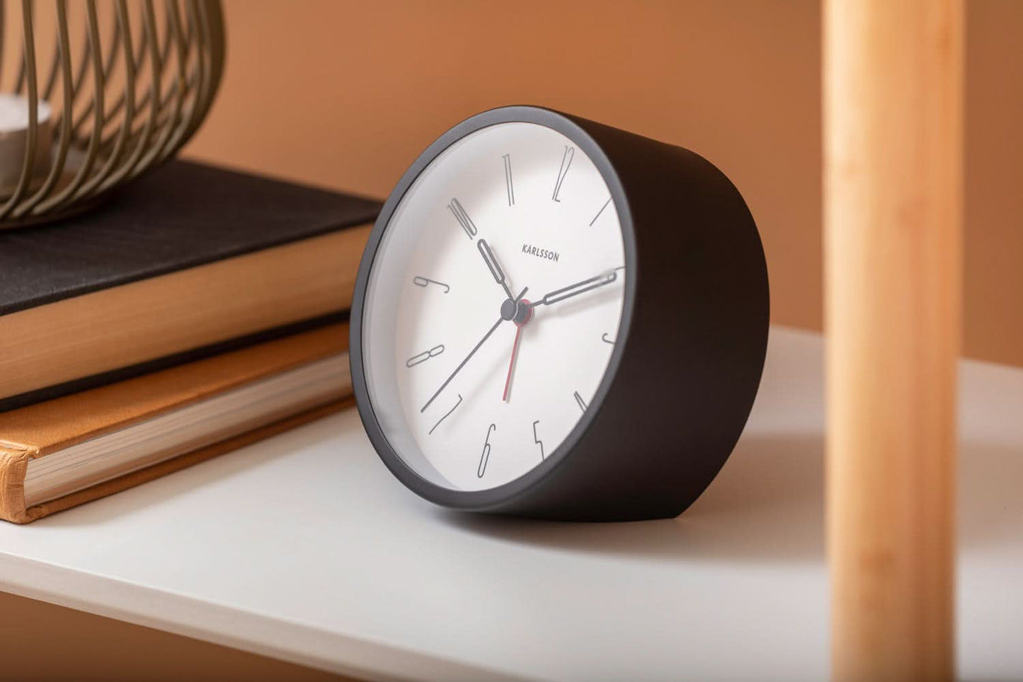Analog väckarklocka med svart hölje, vit urtavla samt minut- och timvisare.