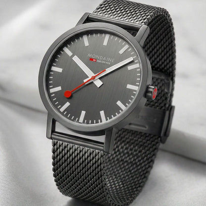 Mondaine herrklocka med mörk urtavla, mesh-armband och röda visare