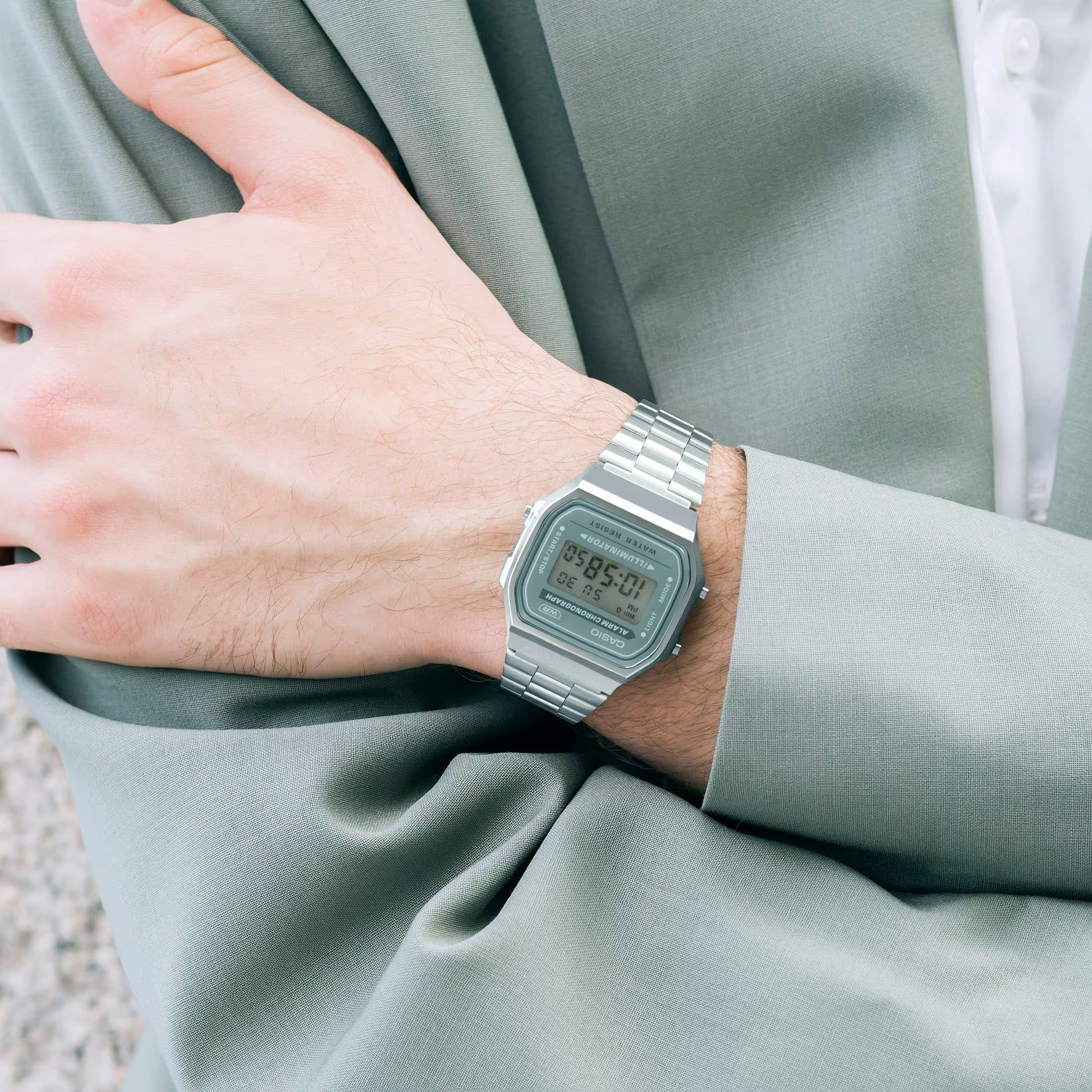 Digital klocka med metallarmband och grön rektangulär urtavla