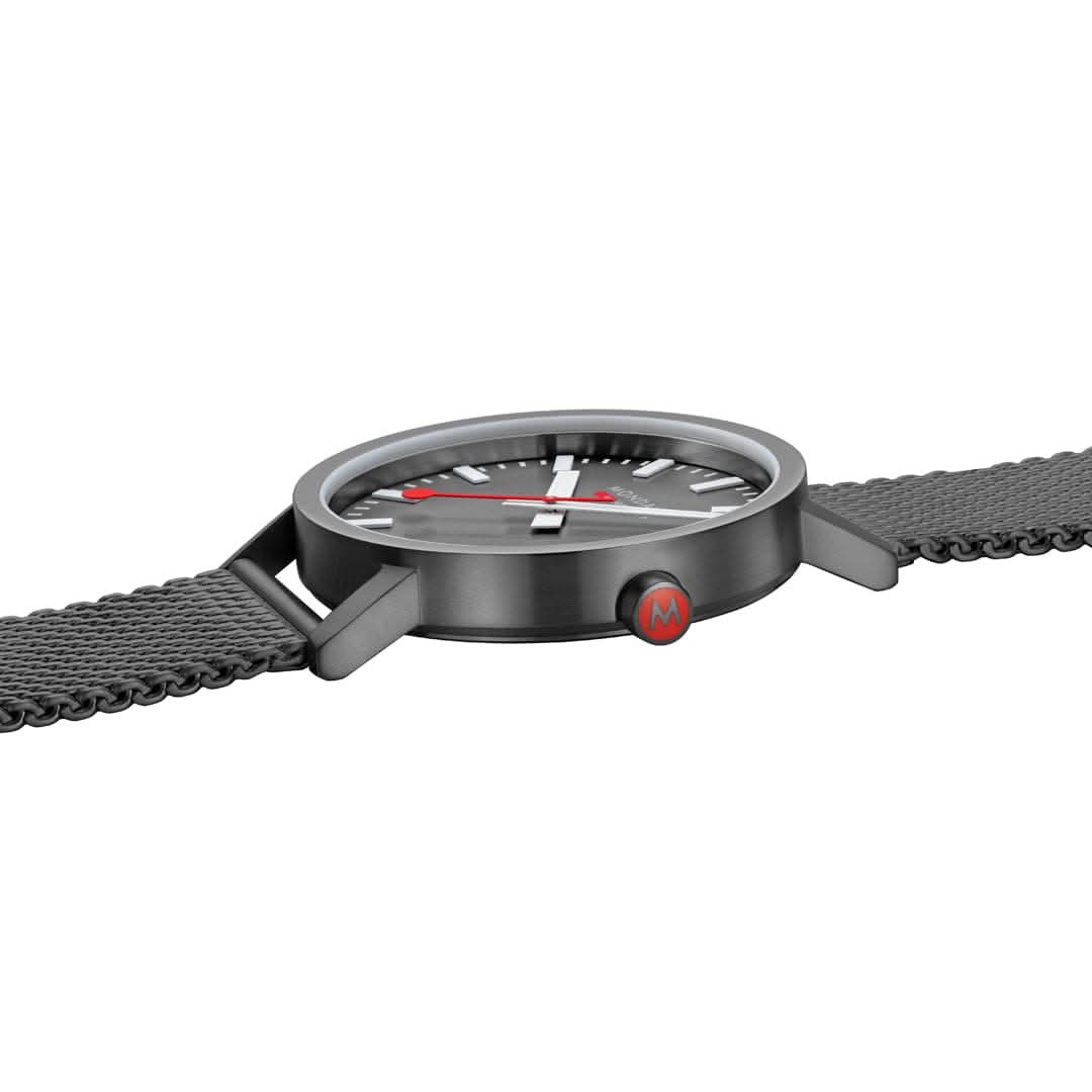 Mondaine herrklocka från sidan: runt boett med urtavla och svart mesh-armband