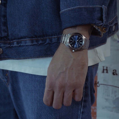 Herrklocka på handleden med blå urtavla och silverfärgat metallarmband