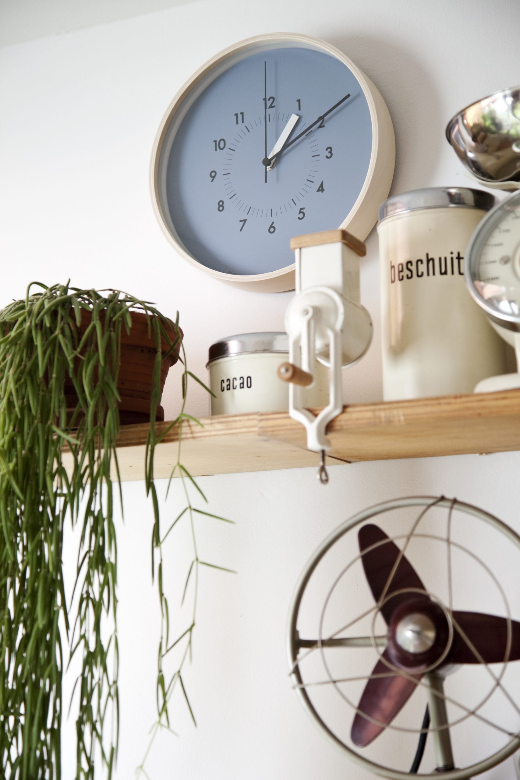 Blaue Wanduhr mit hellem Rahmen, römischen Ziffern und dunklen Zeigern