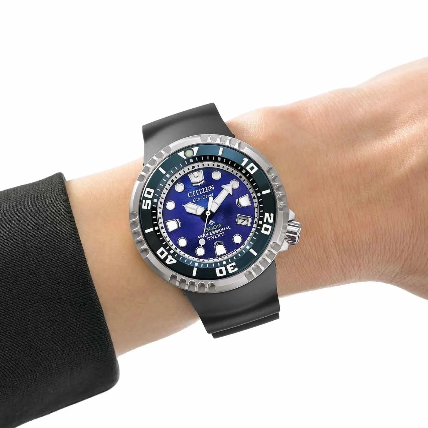 Herrklocka på handleden med svart gummiarmband, blå urtavla och självlysande visare.