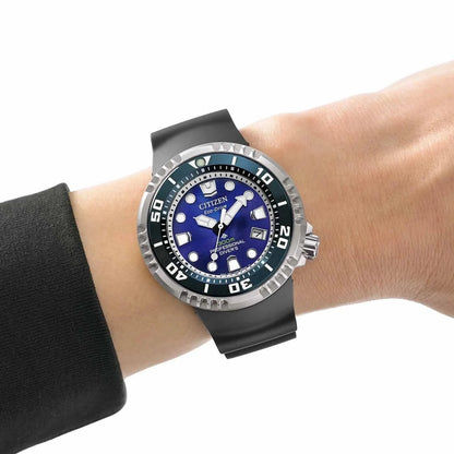 Herrklocka på handleden med svart gummiarmband, blå urtavla och självlysande visare.