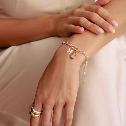 Silverfärgat berlockarmband på handleden med hänge och länkar