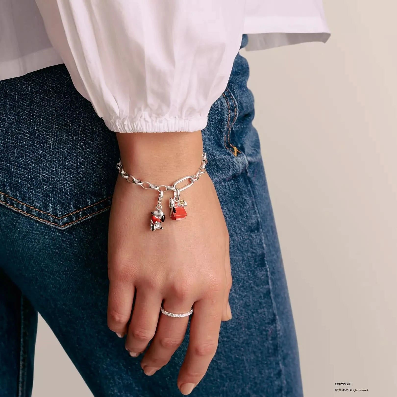 Berlock i silver till armband med figurer av Snoopy och Woodstock vid ett rött hundkoppel