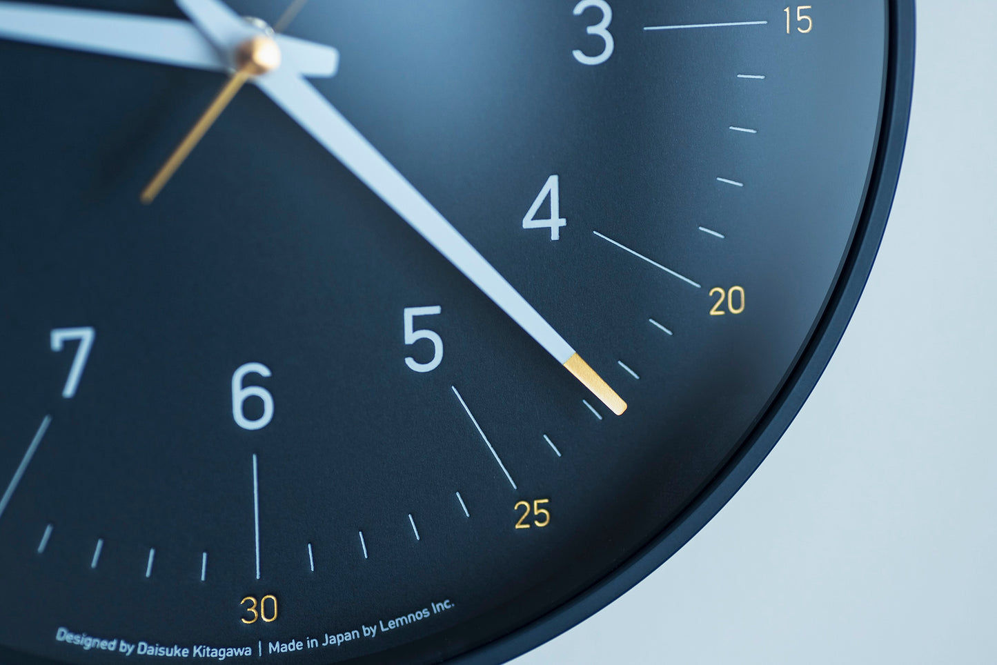 Nahaufnahme von Ziffern und Zeigern einer dunkelblauen Wanduhr am schwarzen Rand