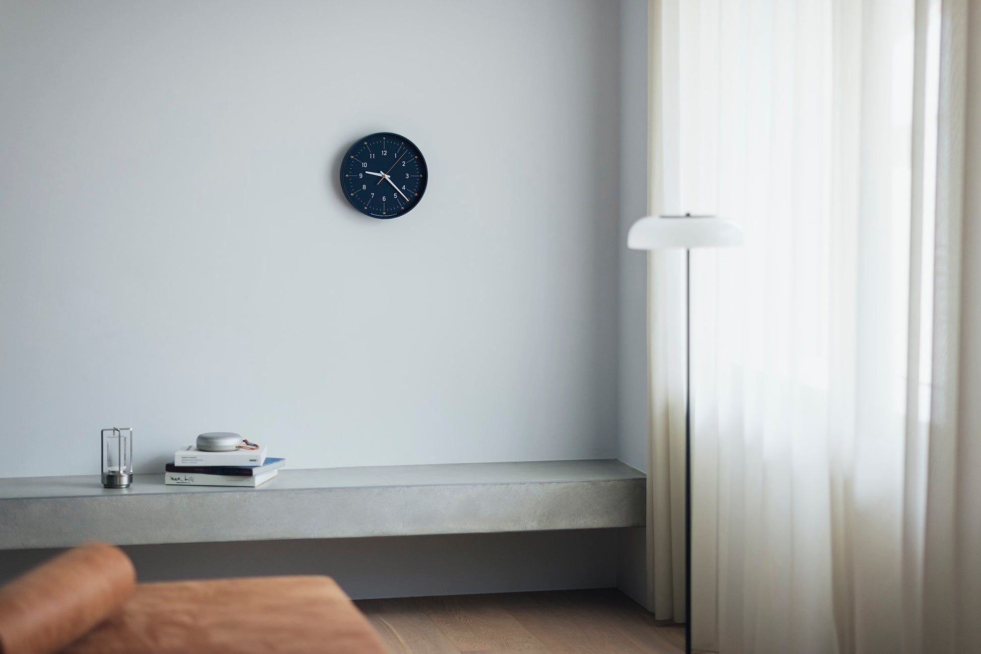 Kleine runde Wanduhr mit dunkelblauem Zifferblatt an der Wand
