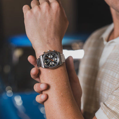 Herrklocka på handleden med silverfärgat metallarmband och svart urtavla