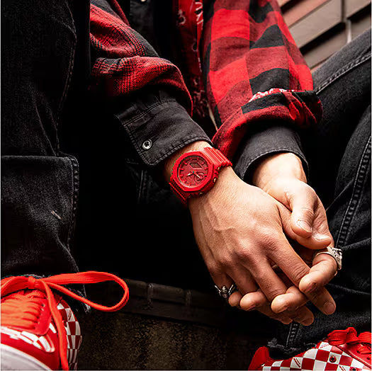 Herrklocka med rött gummiband och rund urtavla, buren på handleden.