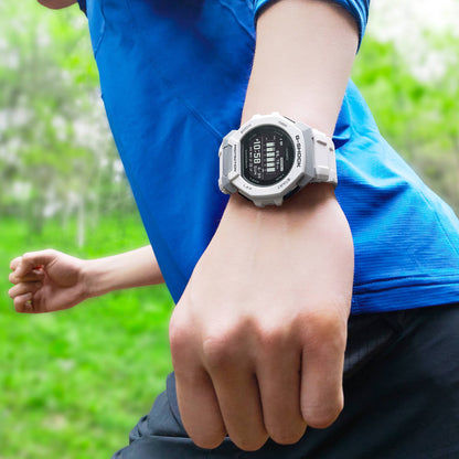 Hand mit blauer Kleidung trägt weiß-graue G-Shock Uhr mit schwarzem Display