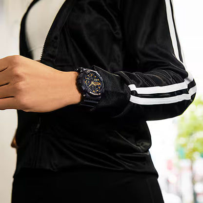 Casio G-Shock damklocka på handleden: svart armband, mörk urtavla med gulddetaljer