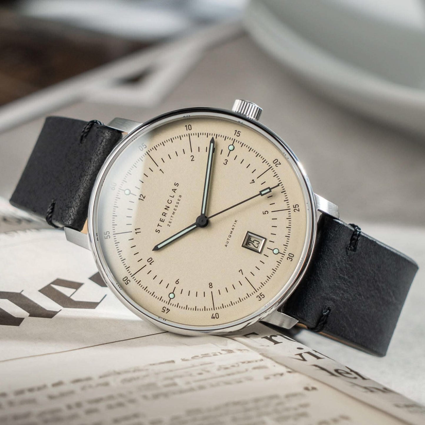 Herrklocka med beige urtavla, svart läderarmband och silverfärgat hölje