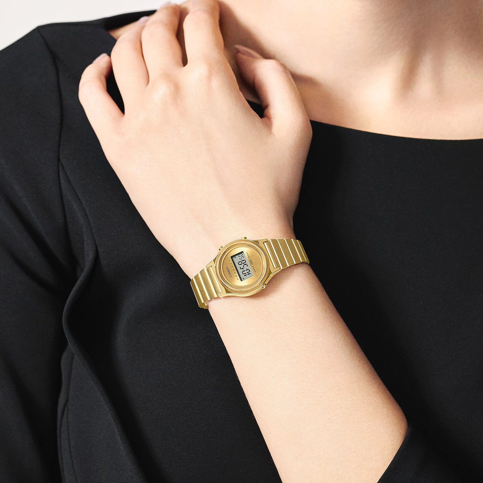 Casio damklocka med guldfärgat metallarmband och rund digital display på handleden