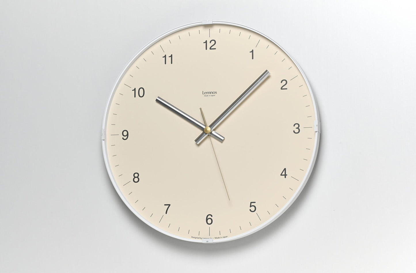 Beige Wanduhr mit silbernem Rahmen, Ziffern und Metallzeigern mit Sekundenzeiger