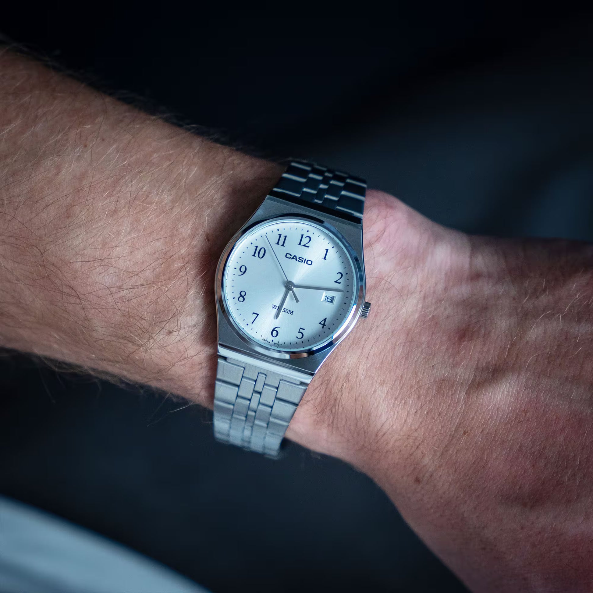 Casio armbandsur med metallarmband och ljusblå urtavla, visare och datumfönster