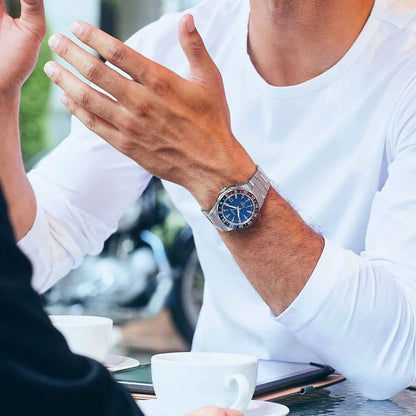 Herrarmbandsur på handleden: blå urtavla och armband i rostfritt stål i affärslook