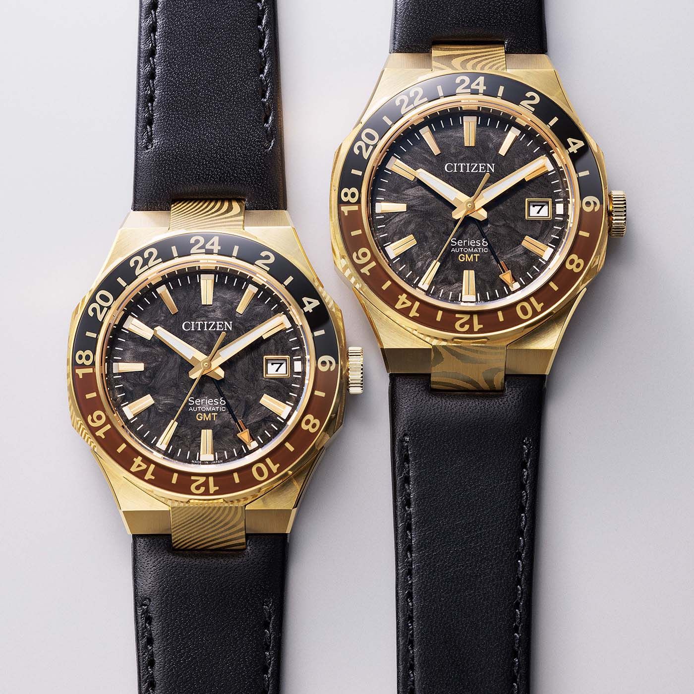 Zwei Armbanduhren nebeneinander: schwarzes Lederband, goldfarbenes Gehäuse, schwarzes Zifferblatt.