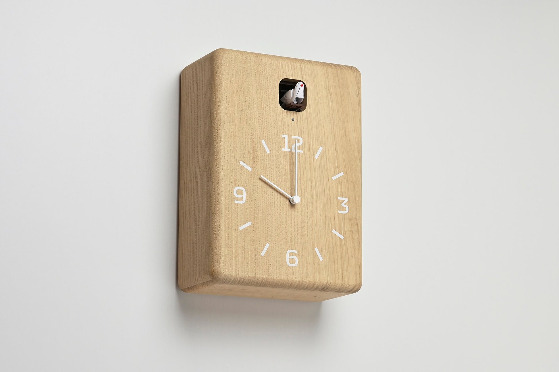 Wanduhr aus hellem Holz, schräger Blick auf das Zifferblatt mit Kuckuckseinsatz
