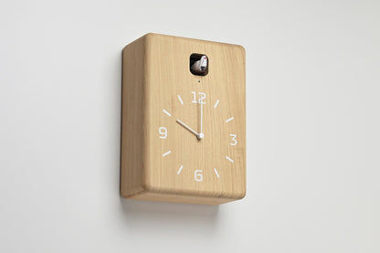Wanduhr aus hellem Holz, schräger Blick auf das Zifferblatt mit Kuckuckseinsatz