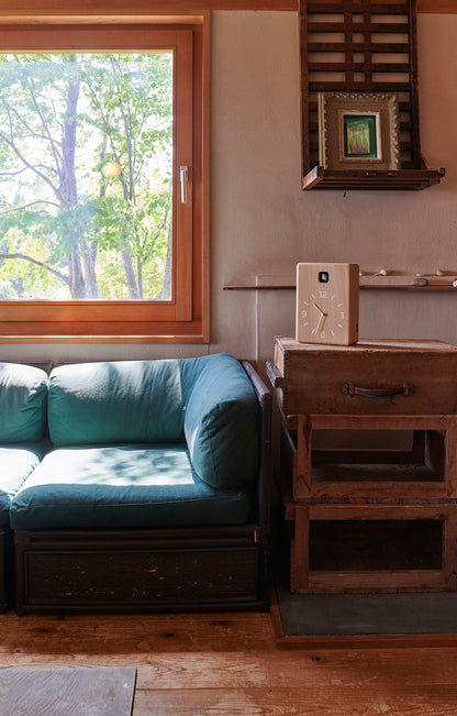Wanduhr aus Holz auf einer Konsole im Wohnraum, sichtbar über dem Sofa