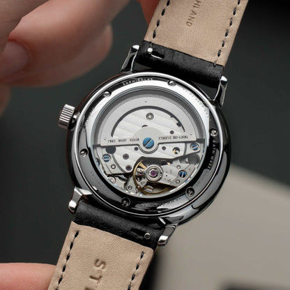 Sternglas herrur med synligt urverk och svart läderarmband med beige söm