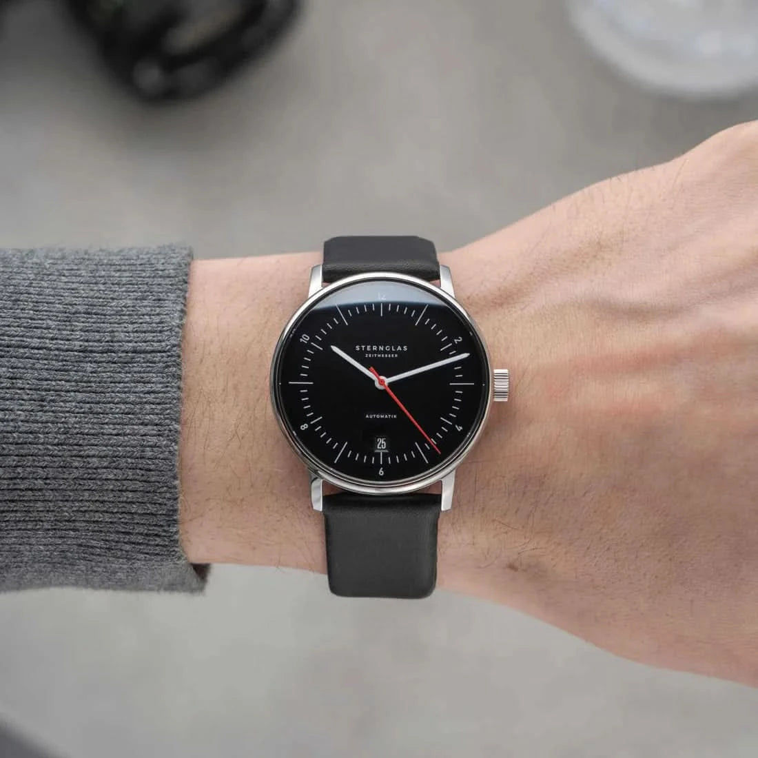 Automatisk unisexklocka på handleden, svart läderarmband och svart urtavla med röda visare