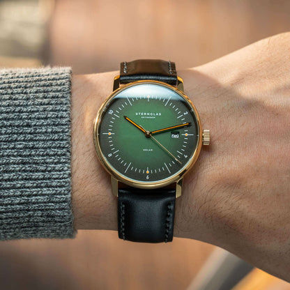 Herrklocka på handleden: grön urtavla, guldfärgat hölje, svart läderarmband