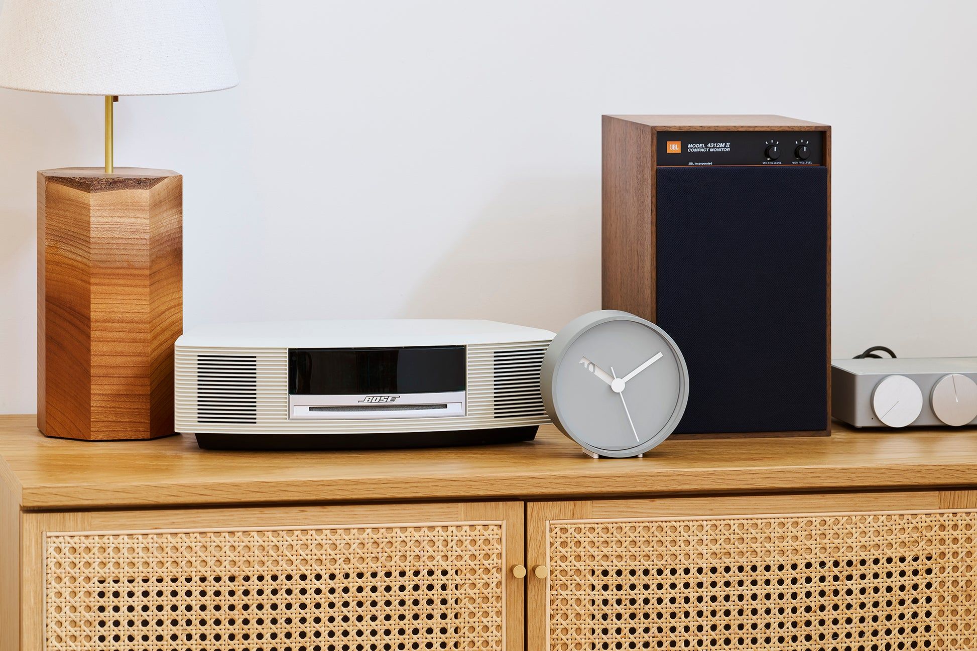 Runde analoge Wanduhr in Grau mit weißen Zeigern, seitlich gekippt und sichtbar