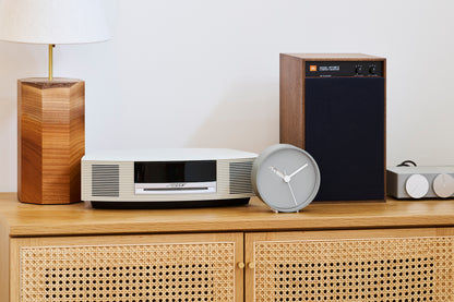 Runde analoge Wanduhr in Grau mit weißen Zeigern, seitlich gekippt und sichtbar