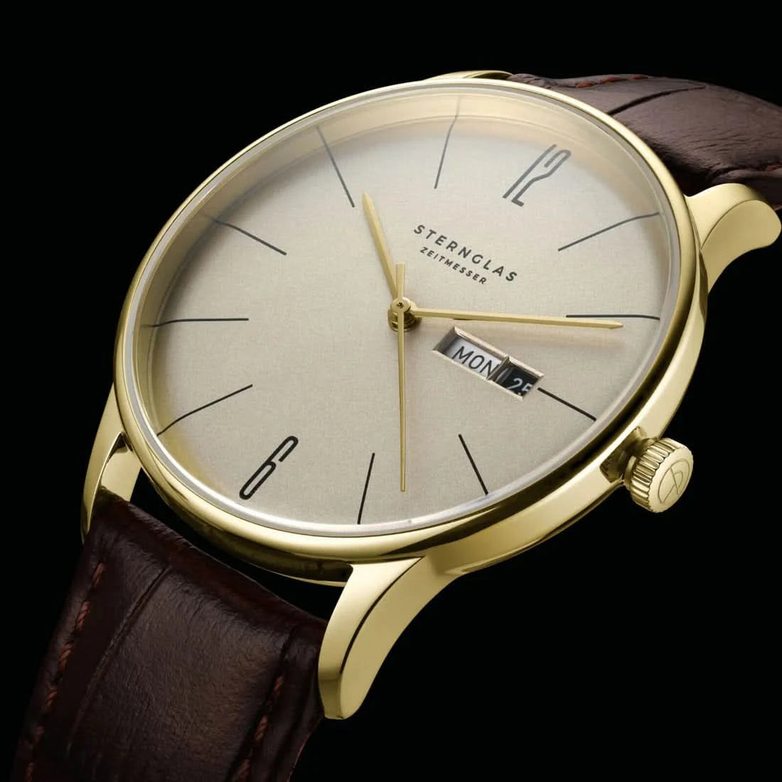 Detaljerad vy av unisexklockan: beige urtavla, guldfärgad krona och brunt läderarmband