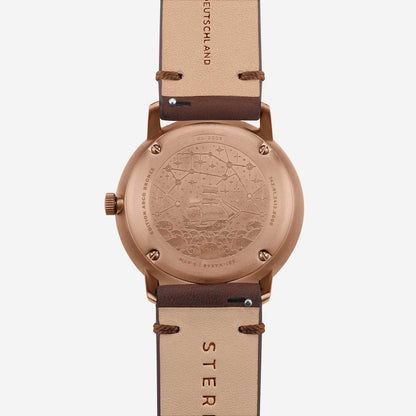 Herrklocka baksida: roséguldigt fodral med prägling, brunt läderarmband