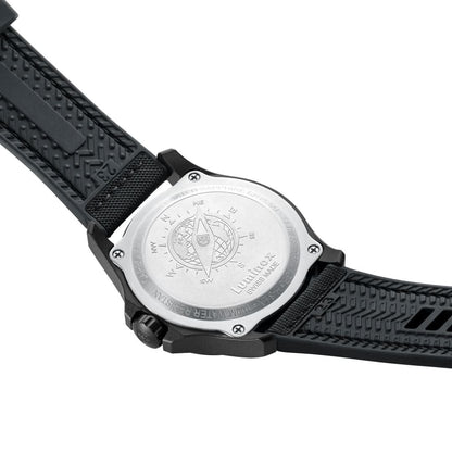 Herrklocka, baksida: silverfärgat hölje med gravyr och svart textilarmband