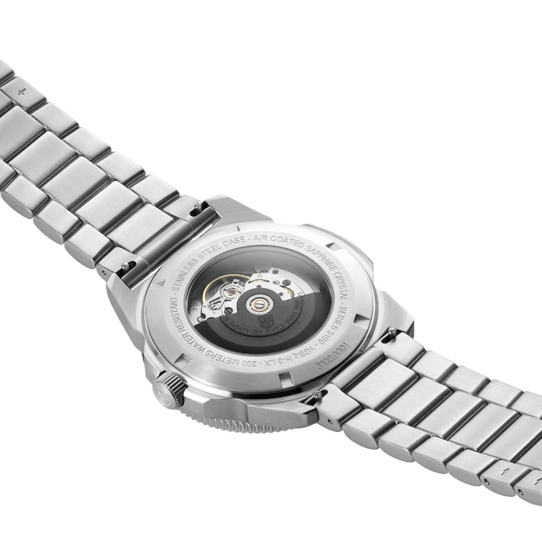 Armbandsur med synligt urverk i boettlocket och armband i rostfritt stål.
