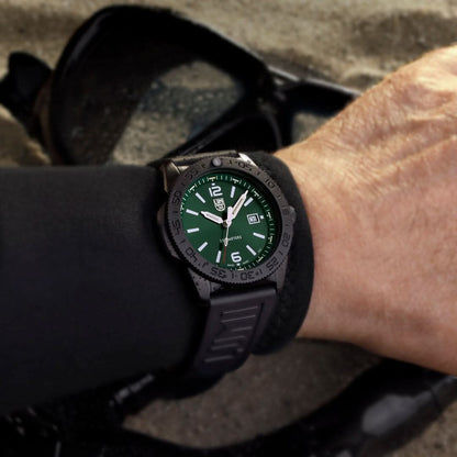 Herrklocka på handleden med svart gummiarmband och grön urtavla