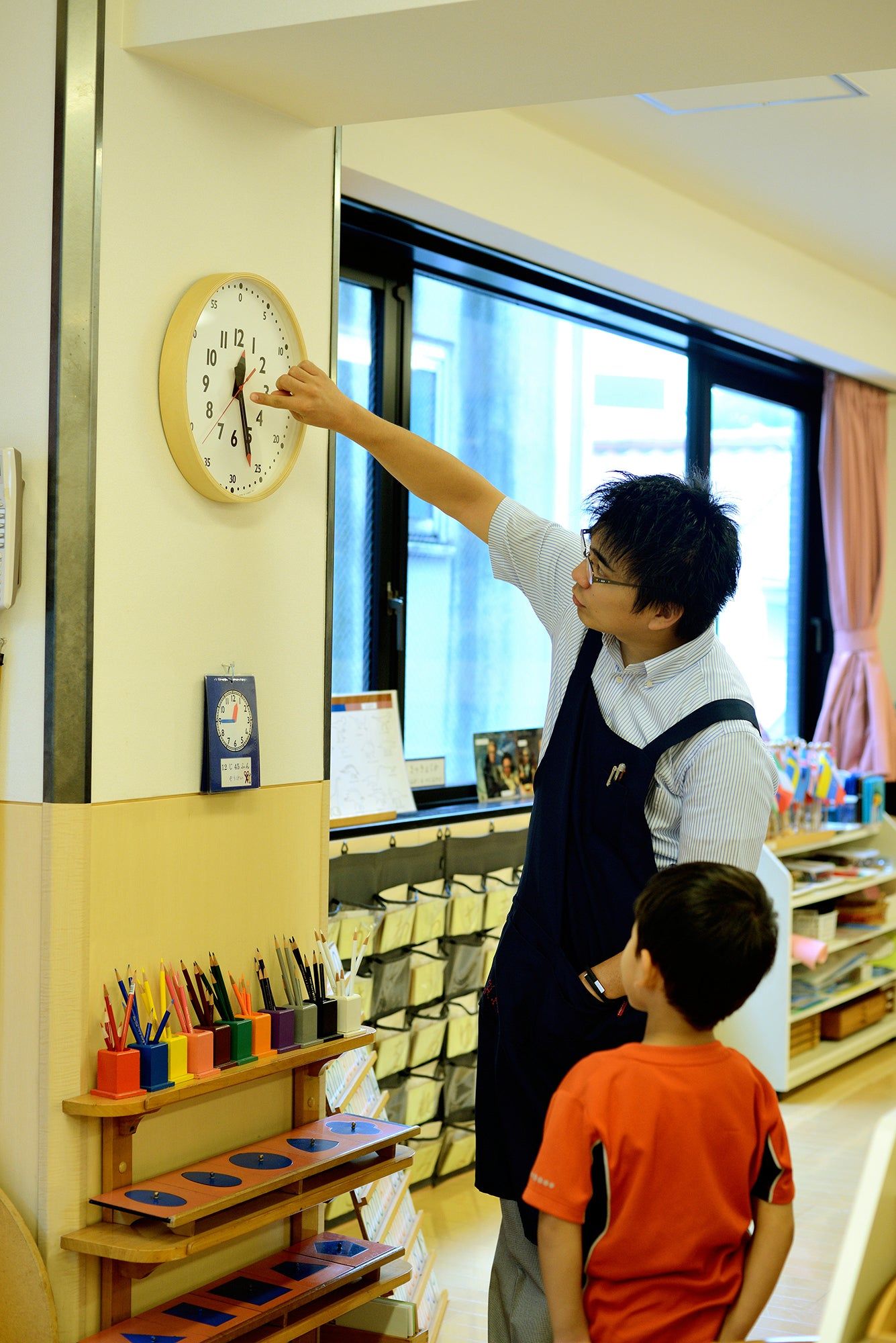 Wanduhr an der Wand mit Naturholzrahmen, Zeigerstellung nahe 12 und rotem Sekundenzeiger