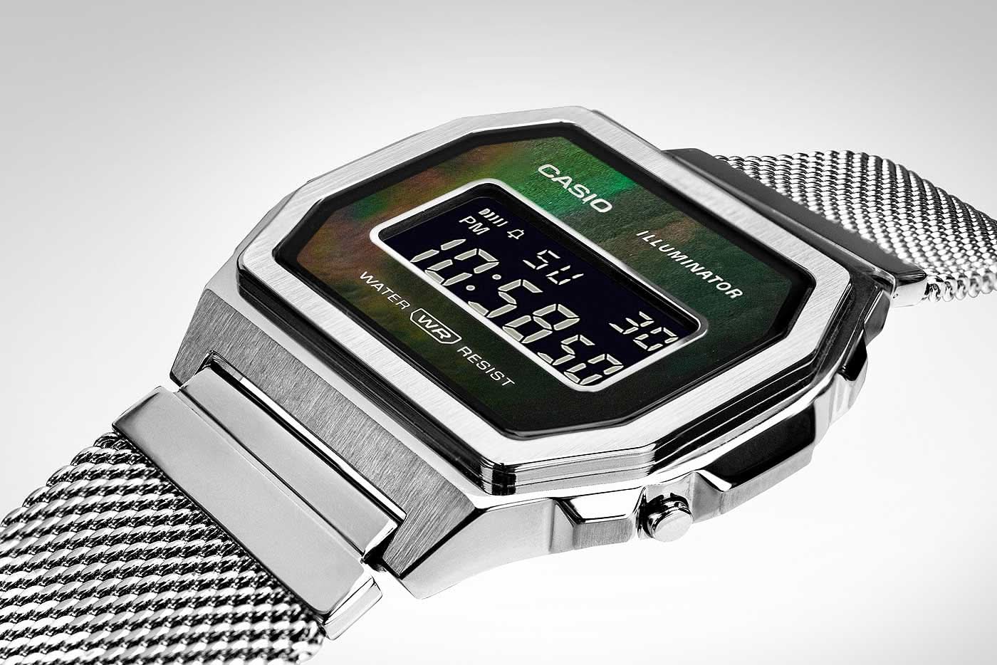 Digital klocka med silverfärgad boett, grönbelyst LCD-display och mesharmband