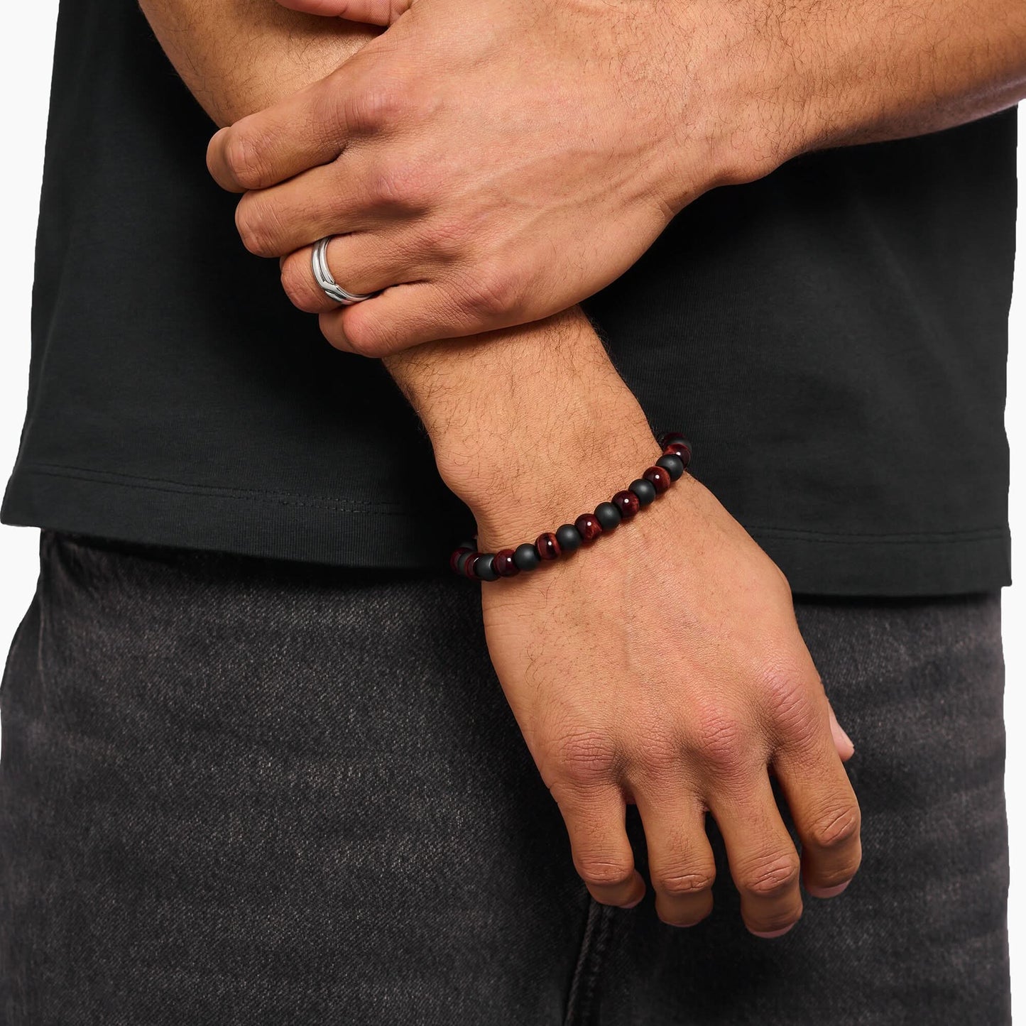 Pärlarmband av obsidian och tigeröga från Thomas Sabo på handleden, runda pärlor