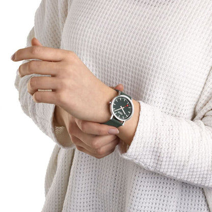 Unisex-armbandsur på handleden med mörkgrön urtavla och grönt textilband.