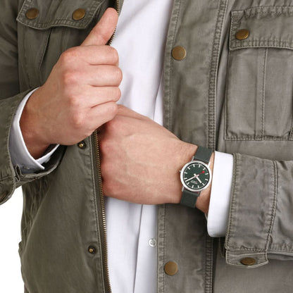 Armbandsur på handleden med mörkgrön urtavla och grönt textilband.