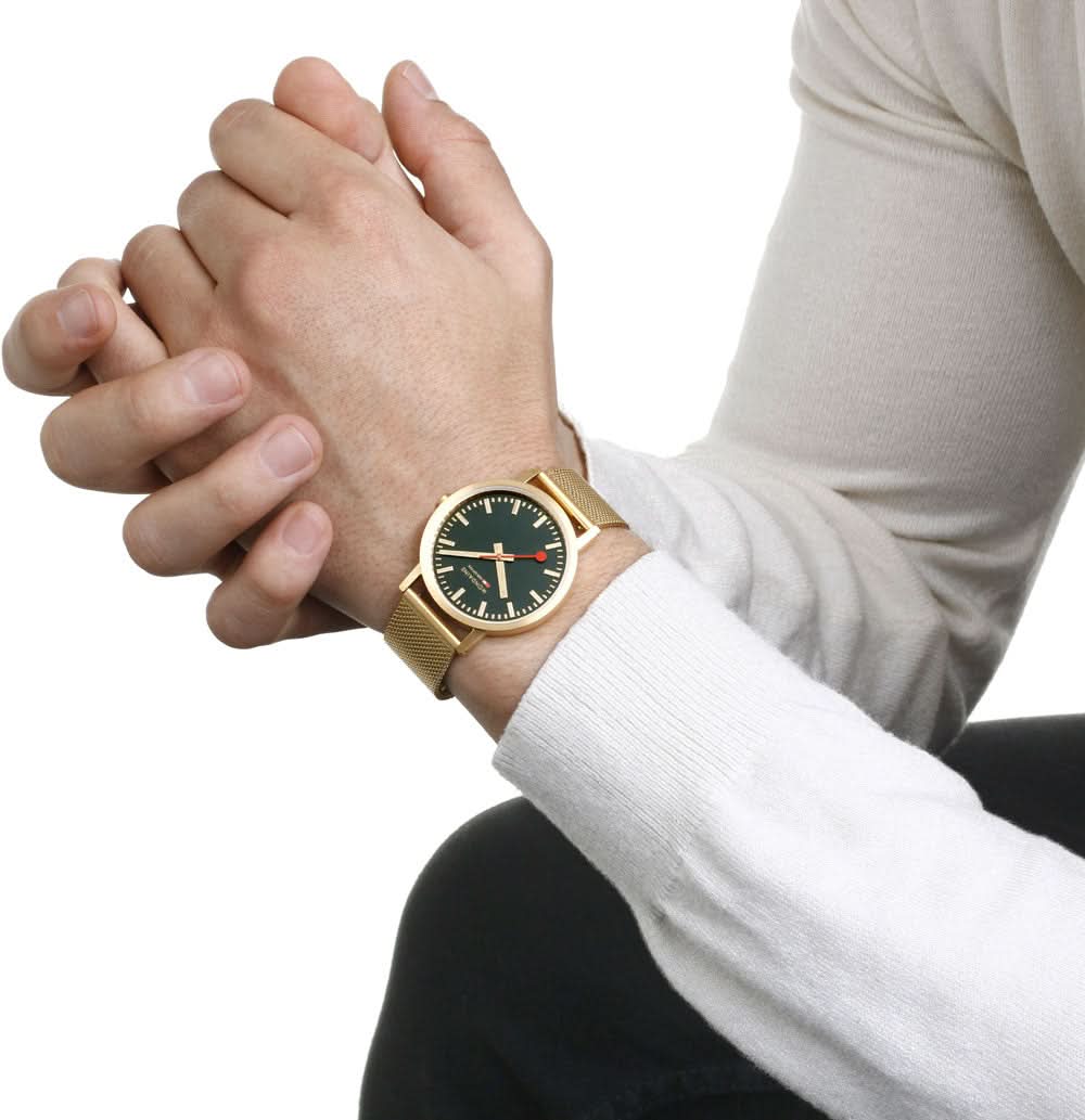 Unisex-armbandsur på handleden med guldfärgat meshband och mörkgrön urtavla