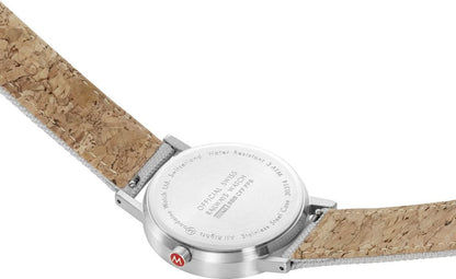 Armbandsur med brunt band i korklook; boettens baksida med text synlig.