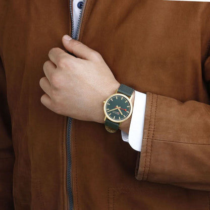 Unisex-armbandsur på handleden med mörkgrön urtavla och mörkgrönt tygband.