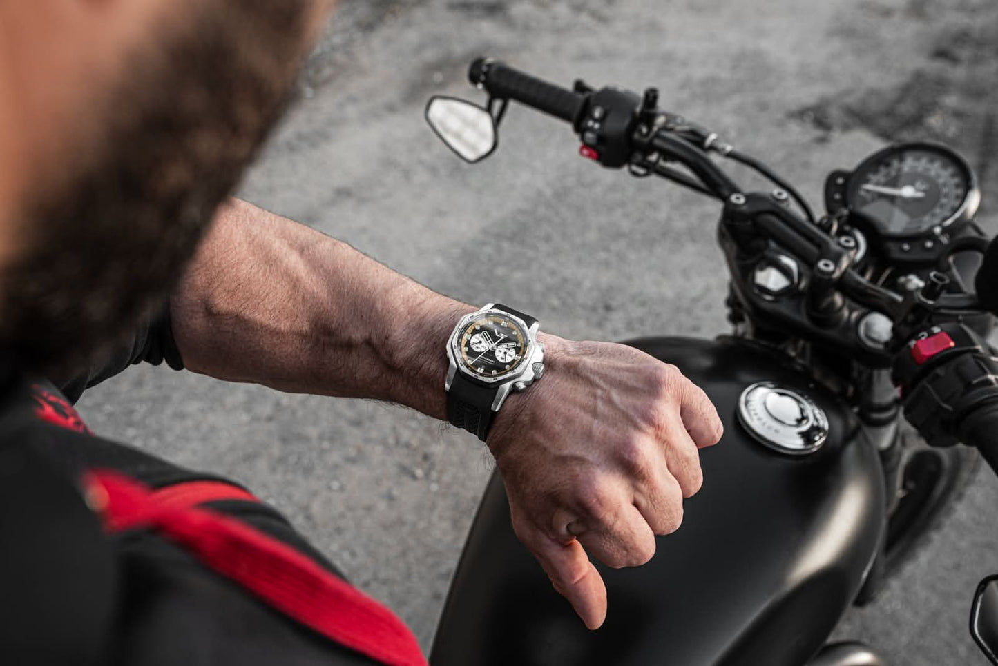 Herrarmbandur på handleden med svart armband bredvid motorcykel